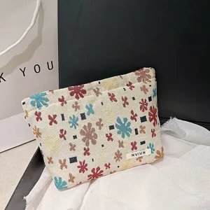 Woven jacquard cosmetic bag with colorful floral pattern, portable travel makeup pouch.