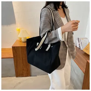 Minimalist large capacity black canvas tote bag with white straps for daily commute casual style.