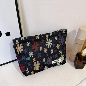 Close-up detail of linen jacquard cosmetic bag with colorful floral pattern and zipper.