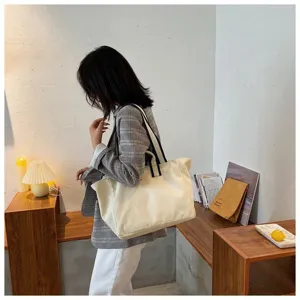 Detailed lifestyle shot of a minimalist canvas tote bag in beige with black straps.