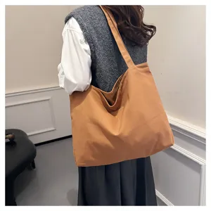 Detail shot of casual brown canvas tote bag, featuring comfortable shoulder strap and spacious design.