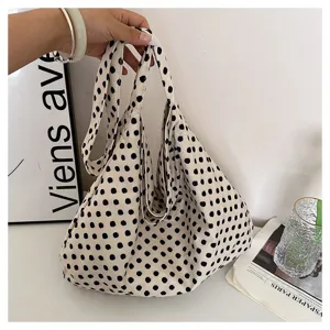 Detailed view of a stylish black and white polka dot canvas tote bag in a clean lifestyle setting.