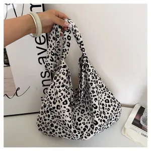 Detailed shot of a stylish black and white leopard print canvas shoulder bag in daily use.
