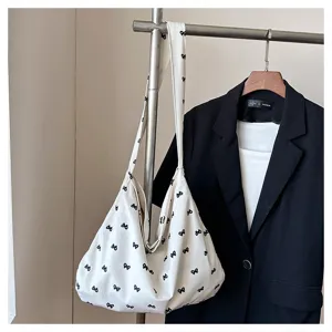 Close-up detail of casual canvas shoulder tote bag with cute black bow print design.