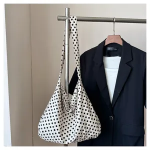 Detailed shot of black and white polka dot canvas shoulder bag hanging in minimalist scene
