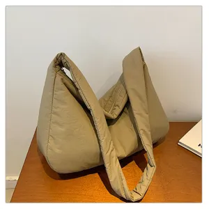 Padded shoulder bag detail showing soft quilted fabric texture and wide strap design.
