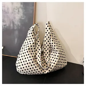 Closeup view of the black and white polka dot canvas tote bag displayed on a dark table.