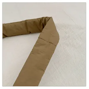 Khaki puffer tote bag strap detail, soft quilted fabric close-up view showing fine stitching.