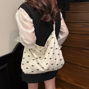 Casual beige canvas shoulder tote bag with cute black bow print for daily women fashion wear.