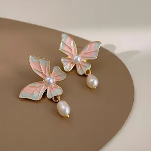Close-up of enamel butterfly freshwater pearl earrings, elegant jewelry detail shot.