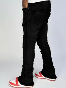 Men's black stacked cargo jeans with distressed details and flared hems for streetwear.