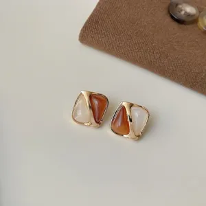 Nahaufnahme von geometrischen zweifarbigen Ohrringen mit braun-weissem Design.