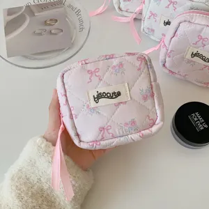 Detailaufnahme einer niedlichen gesteppten Kosmetiktasche mit Blumen und Schleife.