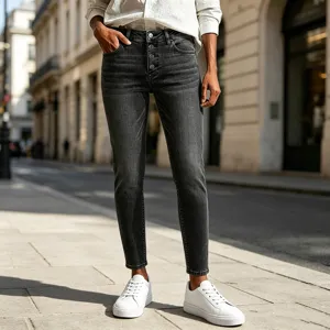Close-up detail of high-waisted button-fly dark grey washed skinny denim trousers in urban street.