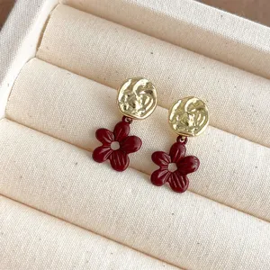 Nahaufnahme von retro burgunderroten Emaille Blumen Ohrringen mit strukturierten Gold.