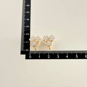 Detailansicht von weißen Blumen-Ohrclips mit vergoldetem Finish und Präzisionslineal.