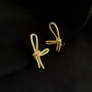 Asymmetrische Schleifen Ohrclips mit funkelndem Zirkon und poliertem Gold für ungepierzte Ohren.