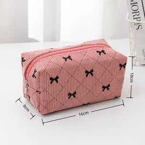Pink corduroy cosmetic bag with black bows, compact and stylish storage pouch detail view.