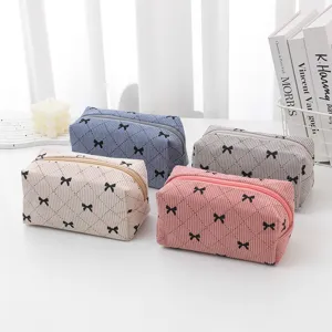 Detail shot of cute corduroy cosmetic bag with bow pattern and zip closure for travel and storage.