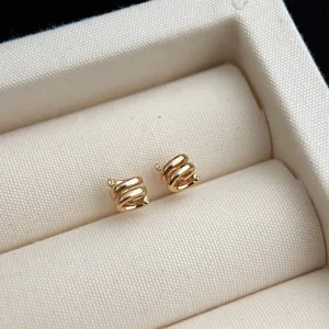 Nahaufnahme von minimalistischen goldenen spiralförmigen Ohrsteckern in Stoffbox.