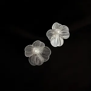 Detailaufnahme der eleganten silbernen hohlen Blumen-Ohrclips mit schöner Perle.