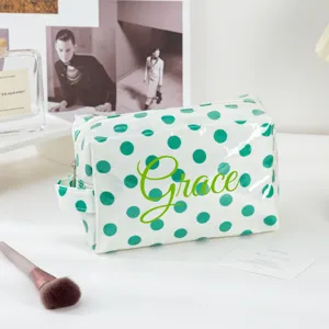 Clear PVC cosmetic bag with green polka dots and custom name, ideal for travel and makeup.