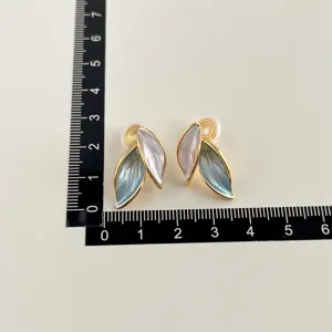 Detailansicht von 18K vergoldeten Blatt-Clip-Ohrringen mit Messskala zur Grössenanzeige.