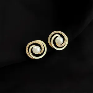 Detailaufnahme von spiralförmigen Gold-Clip-Ohrringen mit weißer Perle und Zirkoniasteinen.