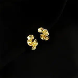 Nahaufnahme von stilvollen gedrehten goldenen geometrischen Ohrringen auf schwarzem Grund.