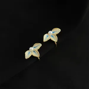 Nahaufnahme eleganter floraler Clip-Ohrringe mit weißen Blütenblättern und Perlenmitte.