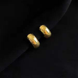 Nahaufnahme Detail von schicken dicken Gold Ohrringen zum Anklipsen auf schwarzer Textur elegant.