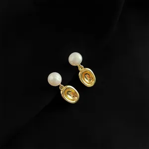 Detailaufnahme eleganter Perlen- und Goldmetall-Ohrringe, raffiniertes Schmuckaccessoire.