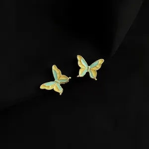 Detaillierte Nahaufnahme eleganter Schmetterlings-Ohrclips mit Goldrand und Emaillierung.