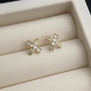 Nahaufnahme der zarten 14K vergoldeten Kreuz Ohrstecker mit funkelnden Zirkonia Steinen.