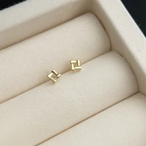 Detailaufnahme minimalistischer goldener geometrischer Ohrstecker in einer eleganten Schmuckbox.