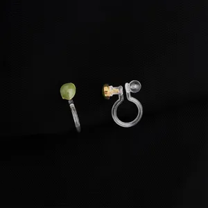 Detailansicht unsichtbarer Ohrclips ohne Ohrlöcher mit grünem Stein und Goldbasis.