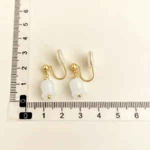 Detailed view of gold-plated clip-on earrings featuring elegant white floral pendants for daily wear.