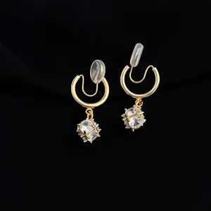 Closeup detail of gold clip-on earrings with sparkling crystal pendant for non-pierced ears.