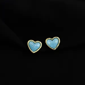 Close-up detail of stylish heart-shaped clip-on earrings with gold trim and blue texture.