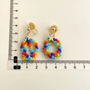 Colorful beaded clip-on earrings detail view with measurement ruler for size reference.
