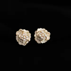 Camellia flower clip-on earrings with white enamel, gold trim and pearl cluster center.