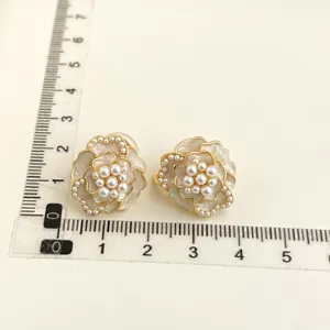 Detailed view of elegant camellia pearl clip-on earrings with size reference ruler.