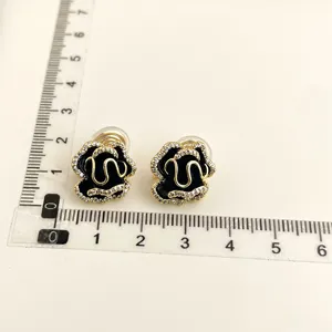 Exquisite black flower clip-on earrings with crystal rim and gold details for non-pierced ears.