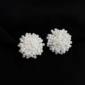 Detailed shot of dense white pearl cluster clip-on earrings, elegant round beaded design.