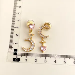 Detailed view of asymmetric gold clip-on earrings with cubic zirconia and pink hearts.