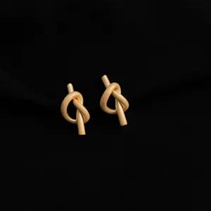 Gold-plated metal knot design clip-on earrings, elegant detail shot for women's fashion wear.