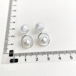 Detailansicht von ohrclips ohne ohrloch mit perlmutt inlays und elegantem spiral design.