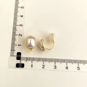 Detailed view of 18K gold plated square pearl clip-on earrings with size measurement ruler.
