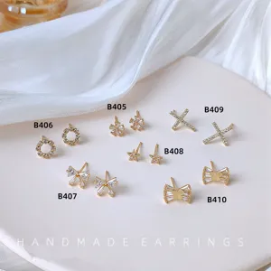 Detailaufnahme von Mini Zirkonia Ohrringen, vergoldet mit Schleife Kreuz und Stern.