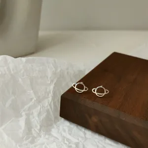 Detailansicht minimalistischer silberner Planeten-Ohrstecker, elegantes Schmuckdesign.